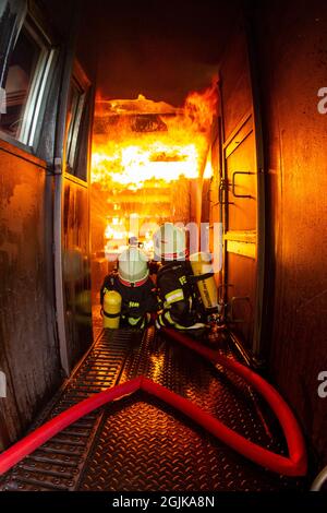 Pirna, Deutschland. September 2021. Zwei Feuerwehrleute bereiten sich im Behälter auf einen Überschlag vor, der gelöscht werden muss. Feuerwehren aus dem Landkreis Sächsische Schweiz-Osterzgebirge zu Szenarien im Feuerwehrtrainingsbehälter. Fisheye shot Quelle: Daniel Schäfer/dpa-Zentralbild/Daniel Schäfer/dpa/Alamy Live News Stockfoto