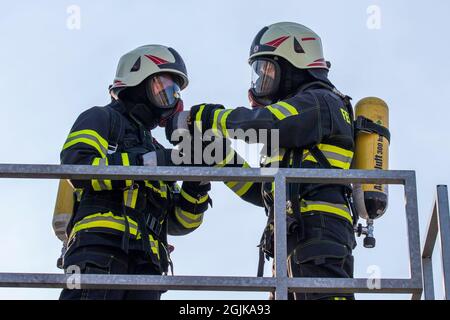 Pirna, Deutschland. September 2021. Zwei Feuerwehrmänner bereiten sich vor, indem sie die Sauerstoffleitung der anderen auf der Schutzmaske überprüfen. Feuerwehren aus dem Landkreis Sächsische Schweiz-Osterzgebirge über Szenarien im Feuertrainingscontainer. Quelle: Daniel Schäfer/dpa-Zentralbild/Daniel Schäfer/dpa/Alamy Live News Stockfoto