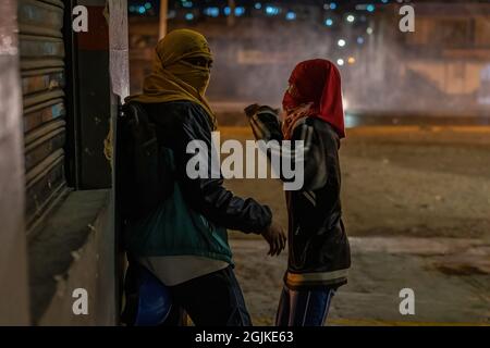 Bogota, Kolumbien. September 2021. Demonstranten decken sich hinter einer Wand, während sie versuchen, Steine auf die Polizei zu werfen. Der Streik ist eine Reaktion auf den Jahrestag, an dem die Polizei vor einem Jahr in Bogota, Kolumbien, in einer Nacht 13 Menschen getötet hat. Der Protest ist Teil eines laufenden nationalen Streiks, der am 28. April in Kolumbien als Reaktion auf Steuerreformen begann, die die Ärmsten des Landes zum Ziel hätten. Kredit: SOPA Images Limited/Alamy Live Nachrichten Stockfoto