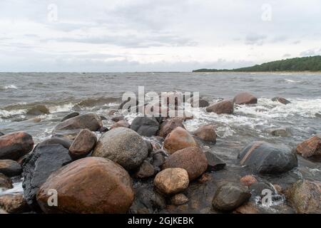 Schöne Aussicht auf die Felsen und Steine im Wasser mit den Bergen im Hintergrund an einem düsteren Tag Stockfoto