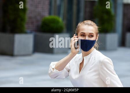 Geschäftsfrau in medizinischer Maske, die am Telefon spricht Stockfoto