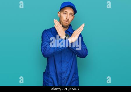 Glatze Mann mit Bart tragen Baumeister Jumpsuit einheitliche Ablehnung Ausdruck Kreuzung Arme tun negative Zeichen, wütend Gesicht Stockfoto