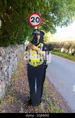 Karton-Ausschnitt gefälschte Verkehrspolizist mit Geschwindigkeitskanone auf 20mph Geschwindigkeitsbegrenzungsschild angebracht, Fortinghall, Perth und Kinross, Schottland, Großbritannien Stockfoto