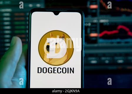 Spanien. September 2021. Das Dogecoin-Kryptowährungslogo ist auf dem Display eines Mobiltelefons mit einem Laptop mit einem Aktienkurrendiagramm im Hintergrund in Barcelona, Spanien, am 10. September 2021 zu sehen (Foto von Davide Bonaldo/Sipa USA) Quelle: SIPA USA/Alamy Live News Stockfoto