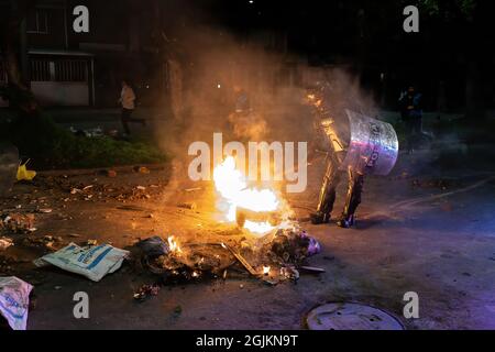 Bogota, Kolumbien. September 2021. Ein Polizeibeamter versucht, das von den Demonstranten während der Demonstration geschaffene Feuer zu löschen. Der Streik ist eine Reaktion auf den Jahrestag, an dem die Polizei vor einem Jahr in Bogota, Kolumbien, in einer Nacht 13 Menschen getötet hat. Der Protest ist Teil eines laufenden nationalen Streiks, der am 28. April in Kolumbien als Reaktion auf Steuerreformen begann, die die Ärmsten des Landes zum Ziel hätten. (Foto von David Lombeida/SOPA Images/Sipa USA) Quelle: SIPA USA/Alamy Live News Stockfoto
