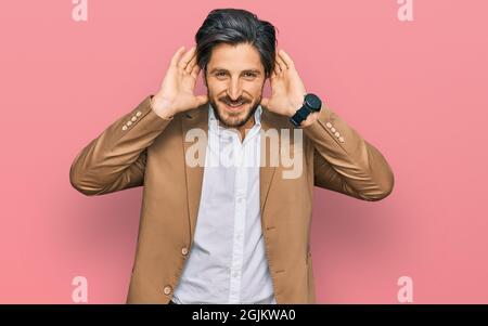 Junge hispanic Mann in Geschäftskleidung versucht, beide Hände auf Ohr Geste hören, neugierig auf Klatsch. Hörproblem, taub Stockfoto