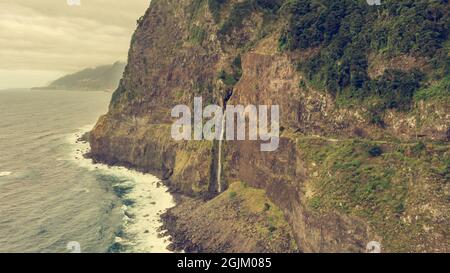 Wasserfall, der von vulkanischen Klippen in den Ozean fällt. Stockfoto