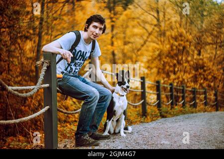 Ein hübscher erwachsener Mann posiert mit seinem Hund Stockfoto