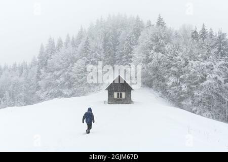 Minimalistischer Winterlandschaft mit Holz- haus und Touristen in der verschneiten Berge. Bewölkt Wetter, Landschaft Fotografie Stockfoto