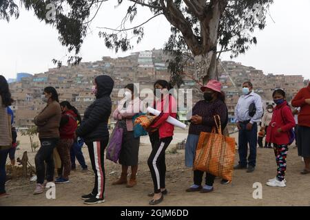 Lima, Peru. September 2021. Menschen mit Mund-zu-Nase-Deckungen stehen inmitten der Corona-Pandemie auf einem Teller mit Lebensmitteln an. Im Bezirk San Juan de Lurigancho wurde die Wasserversorgung für sechs Tage unterbrochen. Kredit: Gian Masko/dpa/Alamy Live Nachrichten Stockfoto