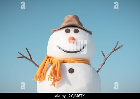 Lustige Schneemann in stilvollen braunen Hut und gelben Skalf auf schneebedeckten Feld. Blauer Himmel auf dem Hintergrund Stockfoto