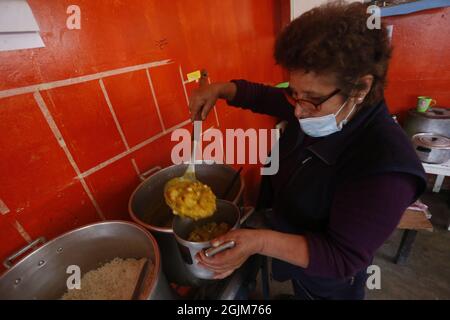 Lima, Peru. September 2021. Eine Frau serviert den Bewohnern während der Corona-Pandemie Essen. Im Bezirk San Juan de Lurigancho hatten die Bewohner seit sechs Tagen keine Wasserversorgung aufgrund eines Rohrbruchs. Kredit: Gian Masko/dpa/Alamy Live Nachrichten Stockfoto