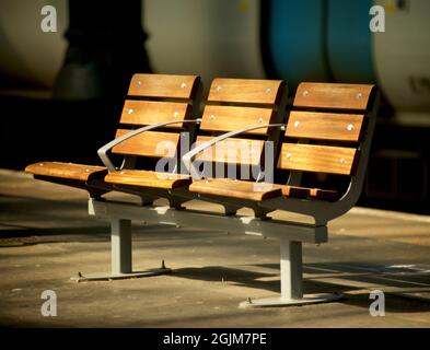 Eine leere, sonnenbeleuchtete Bank am Bahnhof Brighton, Brighton, East Sussex, England, Großbritannien Stockfoto