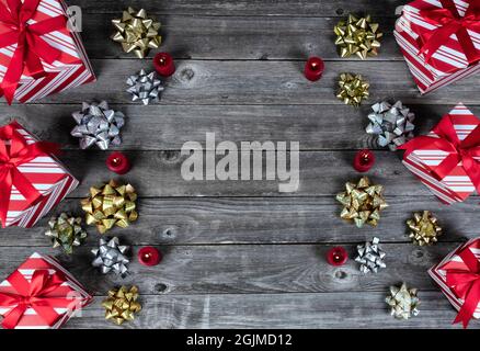 Geschenkboxen, leuchtende Kerzen und Bogenband-Dekorationen auf rustikalen Holzplanken für ein fröhliches Weihnachtsfest oder ein glückliches Neujahrsfest-Konzept Stockfoto