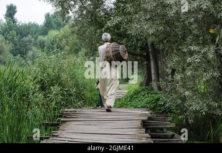 Srinagar, Jammu und Kaschmir, Indien. September 2021. Ein Fußgänger geht über eine Holzbrücke zum schwimmenden Gemüsemarkt auf dem schwimmenden Gemüsemarkt am Dal Lake in Srinagar, am 10. September 2021. Quelle: Adil Abbas/ZUMA Wire/Alamy Live News Stockfoto