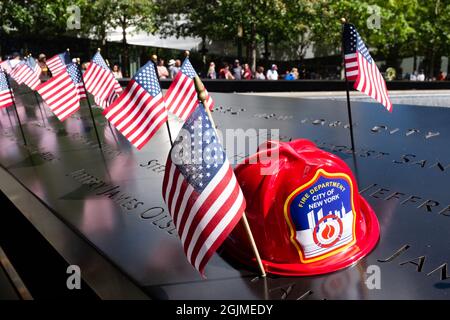 New York, NY, USA. September 2021. Am Tag vor dem 20. Jahrestag der Angriffe des World Trade Center sind offizielle und private Gedenkstätten auf der Gedenkstätte 9/11 zu sehen. Kleine amerikanische Flaggen und der rote Feuerwehrhelm eines Kindes wurden in einem Abschnitt der Gedenkbrüstungshalle platziert, der Feuerwehrleuten gewidmet war, die beim Angriff auf das World Trade Center ums Leben kamen. Quelle: Ed Lefkowicz/Alamy Live News Stockfoto