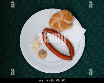 Debrecener-Wurst mit Senf, Meerrettich und Kaiserrolle, serviert auf einem weißen Teller mit Blick von oben Stockfoto