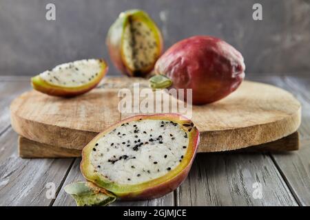 Peruanische Apfelkaktus Früchte ganz und auf Holzständer auf grauem Brett geschnitten. Wissenschaftlicher Name Cereus repandus. Stockfoto