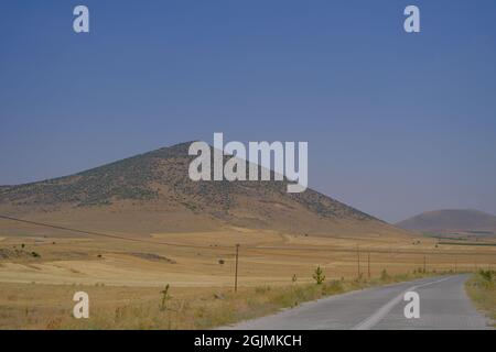 Kleine einhügelige und asphaltierte Straße mit weißen Straßenlinien in Nevsehir Stockfoto