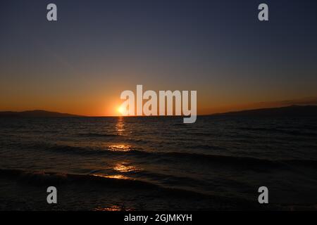 Sommer- und Urlaubsfoto auf dem Meer während des Sonnenuntergangs und herrliche Sonnenreflexion auf dem Wasser mit seiner Reflexion auf dem Himmel Stockfoto