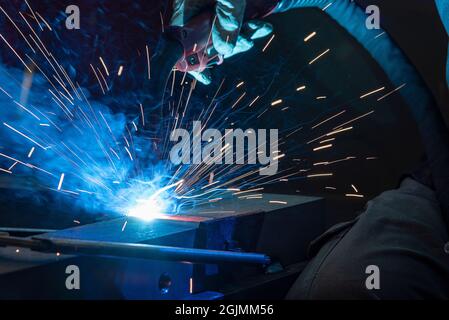 Schweißer mit Schutzmaske, die Metall und Funken schweißen. Industrieller Stahlschweißer im Werk. Stockfoto