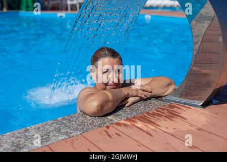 Geothermisches Spa-Zentrum. Die wunderschöne Frau ruht sich aus und führt eine Hydromassage unter dem Wasserfall im tropischen Resort auf dem Meer durch Stockfoto