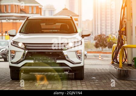 Modernes Auto an einer Tankstelle. Weißer SUV Benzin eingießen. Nahaufnahme Stockfoto