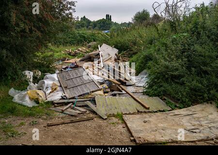 Fly Tipping. Bauherren Müll am Fluss Stort, der auf einem Fußweg neben dem ruhigen Fluss Stort in Hertfordshire, England, abgeführt wird Stockfoto