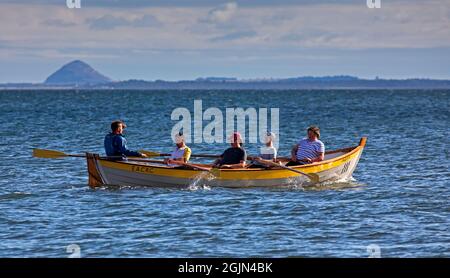 Portobello, Edinburgh, Schottland, Großbritannien, ob. September 2021. Bewölkt mit Sonne und Temperatur von 17 Grad am Meer am Firth of Forth für diejenigen, die Sport treiben. Im Bild: Crew des Edinburgh Amateur Coastal Rowing Club mit Berwick Law im Hintergrund. Stockfoto