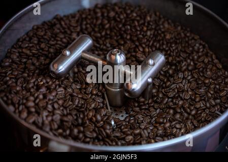 Frische Kaffeebohnen auf Edelstahltrommel Prozess in Rösterei auf dunkel und selektiven Fokus. Frisch geröstete Kaffeebohne in einen sich drehenden Kühlerprofi Stockfoto