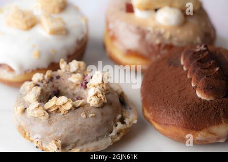 Nahaufnahme mehrerer Arten von Donuts auf einer Marmorplatte, Essen Stockfoto