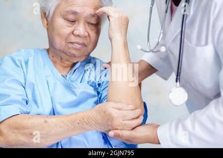 Asiatische ältere oder ältere alte Dame Frau Patientin fühlen Schmerzen ihren Ellbogen auf dem Bett in der Krankenpflege Station, gesund starke medizinische Konzept. Stockfoto