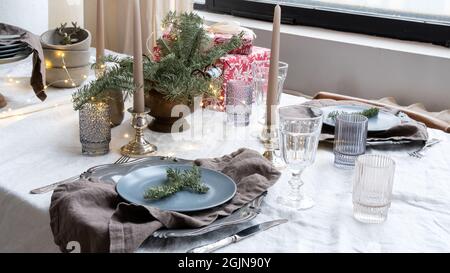 Gläser, Kerzen, Geschenkschachteln und leichte Girlande für die Einrichtung von Esszimmer und Küche. Tischstimmung für ein Weihnachtsessen mit Gästen. Ideen für die Dekoration Stockfoto