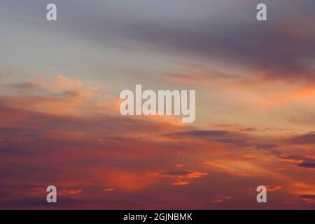 Farbenfrohe, feine, flauschige Wolken am blauen Himmel bei Sonnenuntergang. Mischung aus hellen und pastellfarbenen Farbtönen Stockfoto