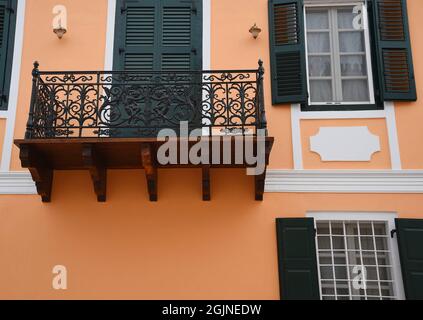 Neoklassizistische Hausfassade mit venezianischer Stuckwand, Zypressengrünen Fensterläden aus Holz und Balkon mit handgefertigtem Eisengeländer in Galaxidi GR Stockfoto