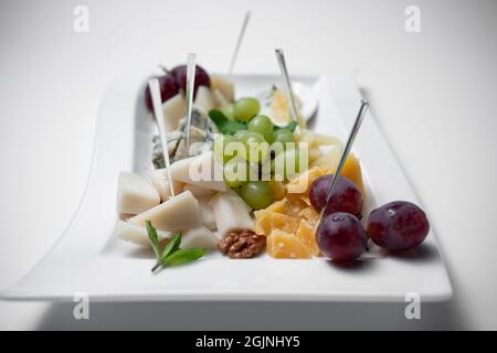 Nahaufnahme des Käseplattes mit Trauben, Walnüssen und Honig auf weißem Hintergrund Stockfoto