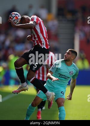 Brentfords Ethan Pinnock (links) führt den Ball klar vor Brighton und Hove Albions Neal Maupay während des Premier League-Spiels im Brentford Community Stadium, London. Bilddatum: Samstag, 11. September 2021. Stockfoto