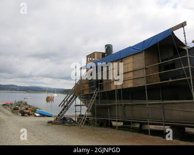 Blaue Markise über den Restaurierungsarbeiten auf Auld Reekie, einem VIC 27 Dampfpuffer auf dem Crinan Boatyard; zuvor als Vital Spark in para Handy zu sehen. Stockfoto