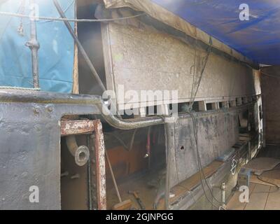 Liebhaber historischer Boote können die Fortschritte bei der Restaurierung des Rumpfes von Auld Reekie auf der Crinan Boatyard beobachten; Installation einer neuen Stahlplatte. Stockfoto