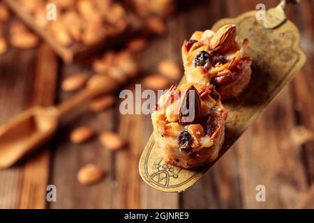 Kleine Kuchen mit Mandeln, Rosinen und Honig auf einem alten Messingspatel. Stockfoto