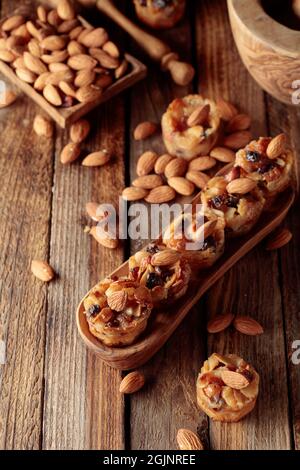Kleine Kuchen mit Mandeln, Rosinen und Honig auf einem alten Holztisch. Stockfoto