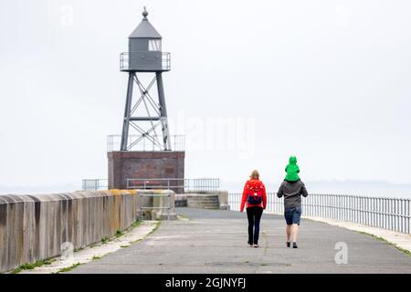 Wilhelmshaven, Deutschland. September 2021. Bei düsterem Wetter geht eine Familie an einem Pier vor dem historischen Kreuzfeuer an der Jade Bay entlang. Quelle: Hauke-Christian Dittrich/dpa/Alamy Live News Stockfoto