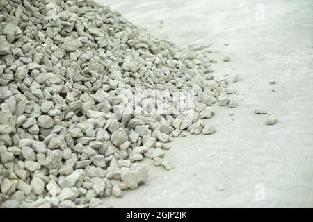 Baumaterial kleiner Stein. Viele Schutt auf der Straße. Eine Rutsche aus weißen Kieselsteinen auf dem Asphalt. Baustelle. Stockfoto