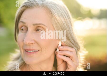 Frau berührt den kabellosen Kopfhörer im Ohr Stockfoto