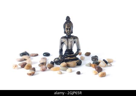 Meditierende Buddha-Statue mit Kieselsteinen isoliert auf weißem Hintergrund. Zen-Garten oder Meditationsort Konzept Stockfoto