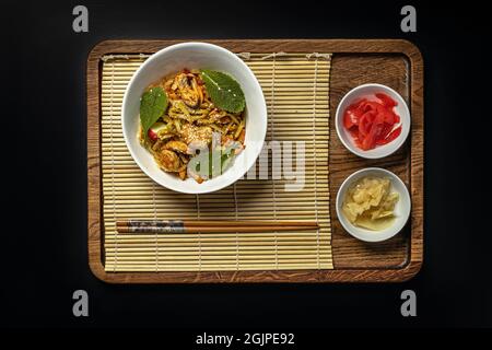 WOK-Nudeln mit Meeresfrüchten und Gemüse. In Öl gebratene Muscheln, Garnelen und Tintenfische. Köstliches asiatisches Mittagessen in einer weißen Schüssel auf schwarzem Hintergrund. Umrühren f Stockfoto