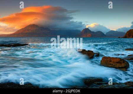 Wellen schlagen gegen Felsen am Elgol Beach mit den Cuilin Mountains in der Ferne, Isle of Skye, Schottland, Großbritannien. Stockfoto