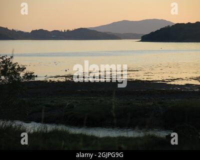 Landschaftlich reizvolle Aussichten auf Schottland: Landschaftsansicht von Loch Melfort bei Sonnenuntergang mit einem goldenen Farbton über der Umrandung der umliegenden Inseln. Stockfoto