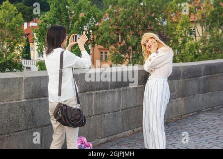 13. August 2017 Prag, Tschechische Republik. Asiatische Touristen werden vor dem Hintergrund der Sehenswürdigkeiten der Stadt fotografiert. Paare nehmen Selfies dagegen Stockfoto