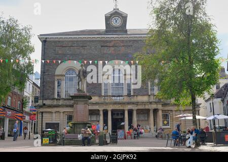 Camarthen Wales 09.11.21. Fußgängerzone. Großes Steingebäude mit drei Bogenfenstern Uhr Stadt. Statue auf einem Sockel. Stühle, Tische im Restaurant Stockfoto